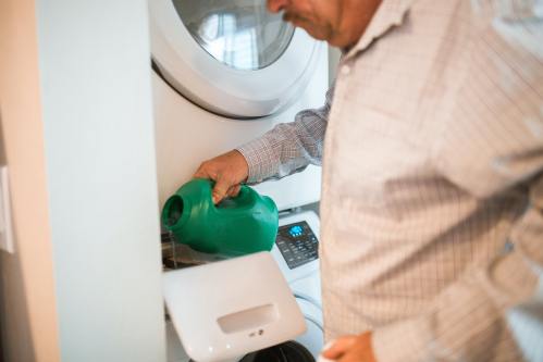 Homme versant liquide dans une machine à laver